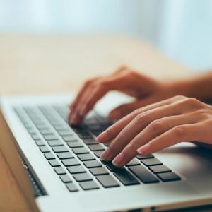 Hands typing on a laptop