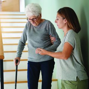 Carer helps senior woman down stairs