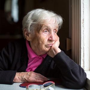 Elderly woman feeling sad as she looks out the window