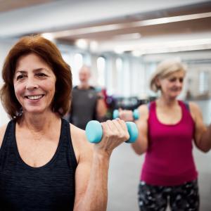 Are you over 50 and looking for fun ways to stay fit and active? A group of over 50s lifting hand weights at the gym class